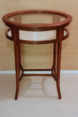 une petite table avec un plateau en verre posée sur un parquet