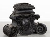 un vase noir orné d'un motif, posé par terre