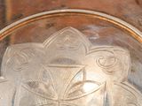 a silver plate with a design on it sitting on a table