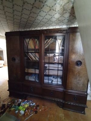 une armoire en bois au milieu d'une pièce où le sol est encombré d'objets divers