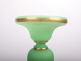 a green vase with a gold rim sitting on a table