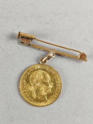 an image of a gold coin and a tie bar on a white surface
