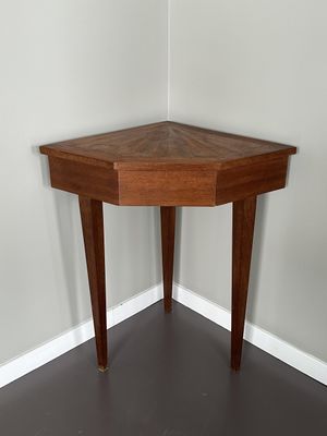 une table d'angle avec un plateau en bois, placée dans un coin de la pièce