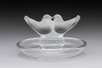 a glass bird on a glass plate on a table