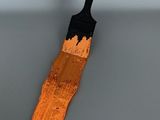 un pinceau orange posé sur une surface grise