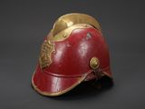 an old red helmet with gold accents on a black background