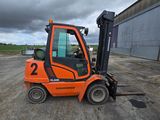 un chariot élévateur orange garé sur un parking
