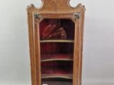 une vieille vitrine en bois contenant des chaussures, posée sur une surface blanche