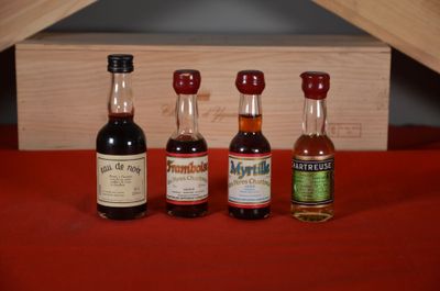 three bottles of liquor sit on a red cloth next to a wooden box