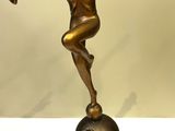 bronze statue of a boy balancing on a ball on a marble base