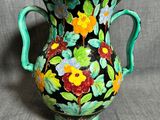 un vase vert orné de fleurs peintes sur fond gris