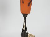 an orange and blue glass vase on a black stand