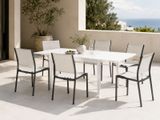 a white table and chairs on a patio with a view of the ocean