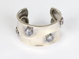 a close up of a silver cuff bracelet with blue stones