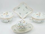a white plate with blue flowers on it next to a bowl and a plate with a lid