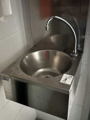un évier en acier inoxydable dans le coin d'une toilette publique