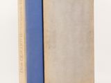 an old book with a blue cover sitting on top of a white surface