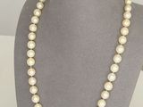 a white pearl necklace on a mannequin with a gold clasp