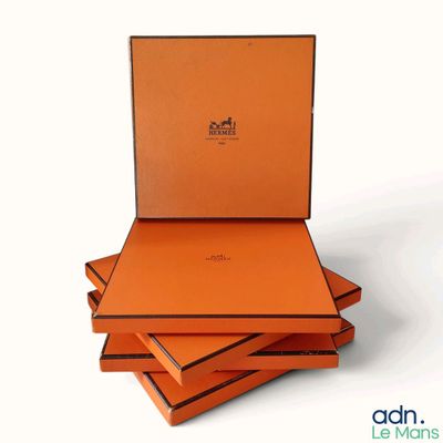 trois boîtes orange sont empilées les unes sur les autres sur une surface blanche