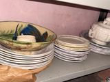 many plates and bowls sitting on a shelf in a room