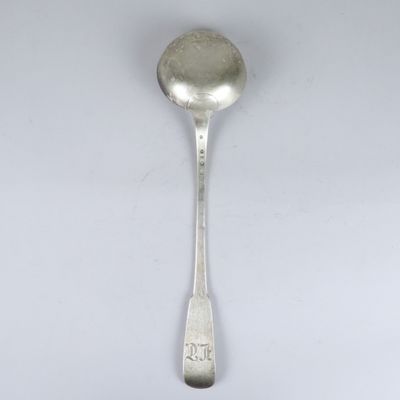 une cuillère ancienne en argent dont le manche repose sur une surface blanche