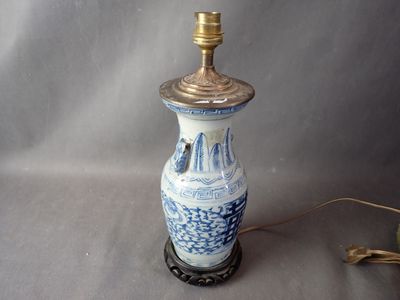 un vase bleu et blanc sur lequel est posée une lampe dorée
