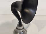 a black horn on a silver base on a white table