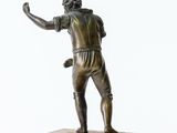 bronze statue of a man holding a tennis racquet on a marble base