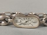 un bracelet en argent orné d'une montre, posé sur une table