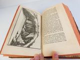 Quelqu'un tient un livre ouvert sur lequel est dessiné le visage d'un homme.