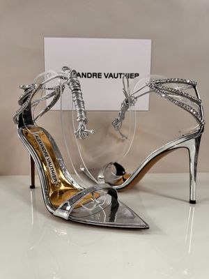 silver and black high heeled sandals on display in front of a sign