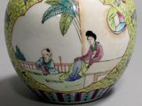 a vase with a painting on it sitting on a table