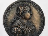 une vieille médaille en bronze représentant une femme avec une fleur dans les cheveux
