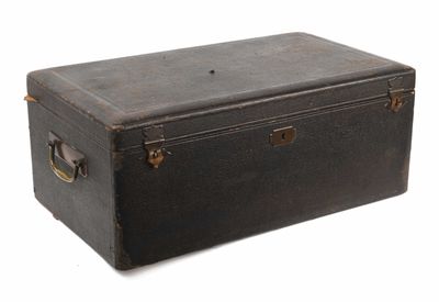 une vieille valise noire posée sur une surface blanche