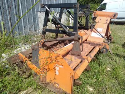 un tracteur immobilisé dans l'herbe, équipé d'une charrue