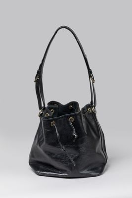 a black leather bucket bag sitting on top of a white surface