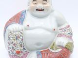a figurine of a laughing buddha sitting on a pillow