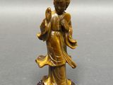 une statue antique en bronze représentant une femme tenant une fleur