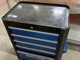 une armoire à outils bleue posée à même le sol dans un garage