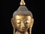 une tête de Bouddha en or posée sur un socle en marbre