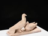 sculpture of two birds sitting on a block on a white surface