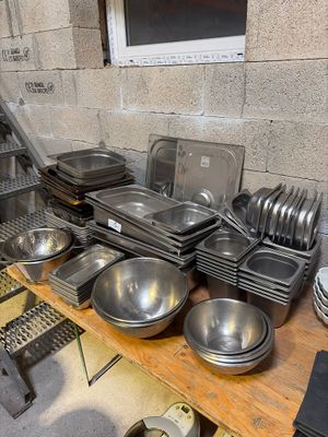 de nombreuses casseroles et poêles posées sur une table dans une cuisine