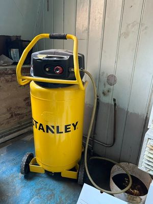 un compresseur d'air Stanley jaune posé sur un chariot dans une pièce