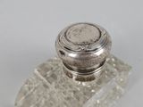 a small silver object on a clear glass base