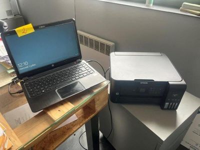 un ordinateur portable posé sur un bureau à côté d'une imprimante