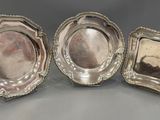 three silverplated dishes, each with a raised edge