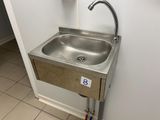 un lavabo en acier inoxydable avec un robinet, situé dans un coin de la salle de bains