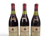 trois bouteilles de vin sont alignées sur une surface blanche
