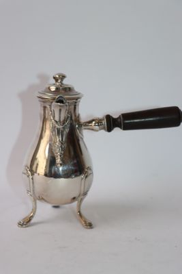 a silver coffee pot with a black handle on a stand