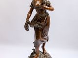 statue en bronze représentant une femme tenant un panier de fleurs, posée sur un socle